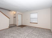 Thumbnail 19 of 21 - A room with a carpeted floor, a door, and a window with blinds.