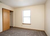 Thumbnail 23 of 24 - A room with a carpeted floor, a door, and a window with blinds.