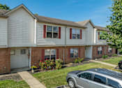 Thumbnail 21 of 23 - A silver car is parked in front of a two-story apartment building with red and white trim.