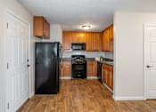 Thumbnail 18 of 23 - A kitchen with a black fridge and wooden cabinets.