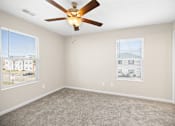 Thumbnail 25 of 28 - an empty living room with a ceiling fan and two windows