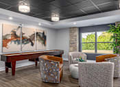 Thumbnail 38 of 57 - A room with a large painting on the wall and a wooden table with chairs around it.