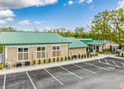 Thumbnail 32 of 57 - A building with a green roof and a parking lot in front.