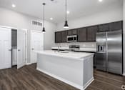 Thumbnail 49 of 57 - A modern kitchen with white countertops and stainless steel appliances.