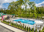 Thumbnail 44 of 57 - A pool surrounded by trees and chairs.