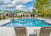 Thumbnail 4 of 57 - A swimming pool with chairs around it and a building in the background.