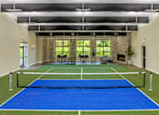 Thumbnail 6 of 57 - A tennis court is set up indoors with a net and two chairs.
