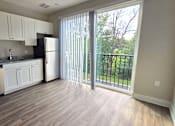 Thumbnail 1 of 16 - Kitchen and living area with balcony of an available apartment unit at Greenwood Commons Apartments in Delaware, OH.