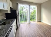 Thumbnail 2 of 16 - Kitchen and living area with balcony of an available apartment unit at Greenwood Commons Apartments in Delaware, OH.