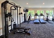 Thumbnail 4 of 16 - A spacious gym with a variety of equipment including treadmills, stationary bike, weights, and benches, located at the clubhouse at Greenwood Commons Apartments in Delaware, OH.