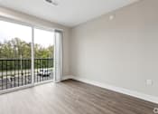 Thumbnail 22 of 33 - A room with a sliding glass door leading to a balcony.