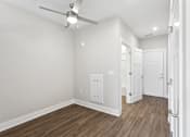 Thumbnail 23 of 33 - A room with a ceiling fan and wooden flooring.