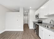 Thumbnail 21 of 33 - A kitchen with white cabinets and a wooden floor.
