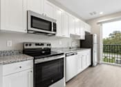 Thumbnail 20 of 33 - A kitchen with black appliances and white cabinets.