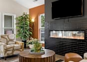 Thumbnail 13 of 33 - A living room with a fireplace and a flat screen TV mounted above it.