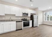 Thumbnail 15 of 33 - A kitchen with white cabinets and stainless steel appliances.