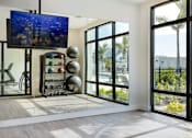 Thumbnail 19 of 49 - A room with a television, a chair, and a ball machine.at Imperial Crossing Luxury Apartment Homes, Bonita Springs