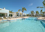 Thumbnail 13 of 49 - A swimming pool surrounded by palm trees and lounge chairs.at Imperial Crossing Luxury Apartment Homes, Bonita Springs, FL