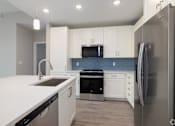 Thumbnail 25 of 49 - A modern kitchen with white cabinets and stainless steel appliances.at Imperial Crossing Luxury Apartment Homes, Bonita Springs, FL