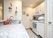 Thumbnail 1 of 17 - A kitchen with white cabinets and a marble countertop.