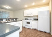 Thumbnail 6 of 17 - A kitchen with white appliances and a granite counter.