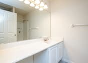 Thumbnail 4 of 17 - A white bathroom with a mirror and lights above it.