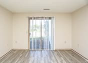 Thumbnail 4 of 26 - A room with a sliding glass door and wooden flooring.