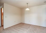 Thumbnail 8 of 26 - A room with a carpeted floor and a hanging light fixture.
