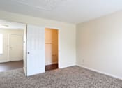 Thumbnail 28 of 30 - A room with a carpeted floor and two doors, one of which is open.