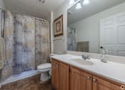 Thumbnail 4 of 27 - A bathroom with a toilet, sink, and shower curtain.