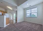 Thumbnail 23 of 27 - A spacious living room with a carpeted floor and a window with blinds.