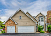 Thumbnail 21 of 27 - A two-car garage is attached to a house with a brick chimney.