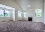Thumbnail 5 of 27 - A large empty room with a fireplace and three windows.