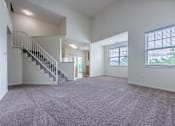 Thumbnail 2 of 27 - A spacious living room with a staircase and large windows.
