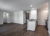 Thumbnail 12 of 27 - an empty kitchen and living room with white walls and wood flooring