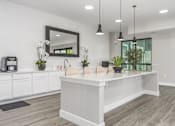 Thumbnail 49 of 53 - A white kitchen with a large island and a mirror above it.