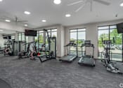 Thumbnail 4 of 53 - A spacious gym with a variety of equipment including treadmills, elliptical machines, and a fan.