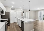 Thumbnail 20 of 71 - Kitchen with quartz countertop, refrigerator, stove, oven, dishwasher, and microwave, and the living area, of an apartment unit at Tiffany Flats in Columbus, OH.