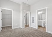 Thumbnail 61 of 71 - Carpeted bedroom, closet, and attached bathroom with ceiling fan of a Tiffany Flats apartment home.