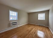 Thumbnail 3 of 21 - an empty living room with wood floors and a radiator and two windows