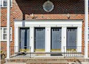 Thumbnail 4 of 13 - A red brick house with a blue front door.