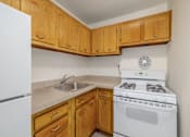 Thumbnail 7 of 13 - A kitchen with a white stove and wooden cabinets.