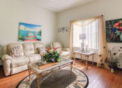 Thumbnail 7 of 12 - Living room with large window, hardwood-style flooring, and model furnishings