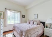 Thumbnail 8 of 12 - bedroom with large window, hardwood-style flooring, and model furnishings