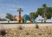 Thumbnail 2 of 13 - a playground in the middle of a dirt field with palm trees in the background