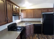 Thumbnail 6 of 13 - an empty kitchen with wooden cabinets and black appliances