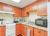 Thumbnail 15 of 22 - kitchen with ample wood cabinetry, granite countertops, and white appliances