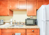 Thumbnail 16 of 22 - wood cabinetry, granite countertops, and stainless steel sink