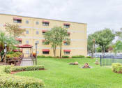 Thumbnail 4 of 24 - lush lawn at Casa San Pablo Senior Apartments with mature trees and decorative grasses