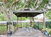 Thumbnail 23 of 24 - outdoor pavillion with seating under a canopy beside iron fence with potted plants